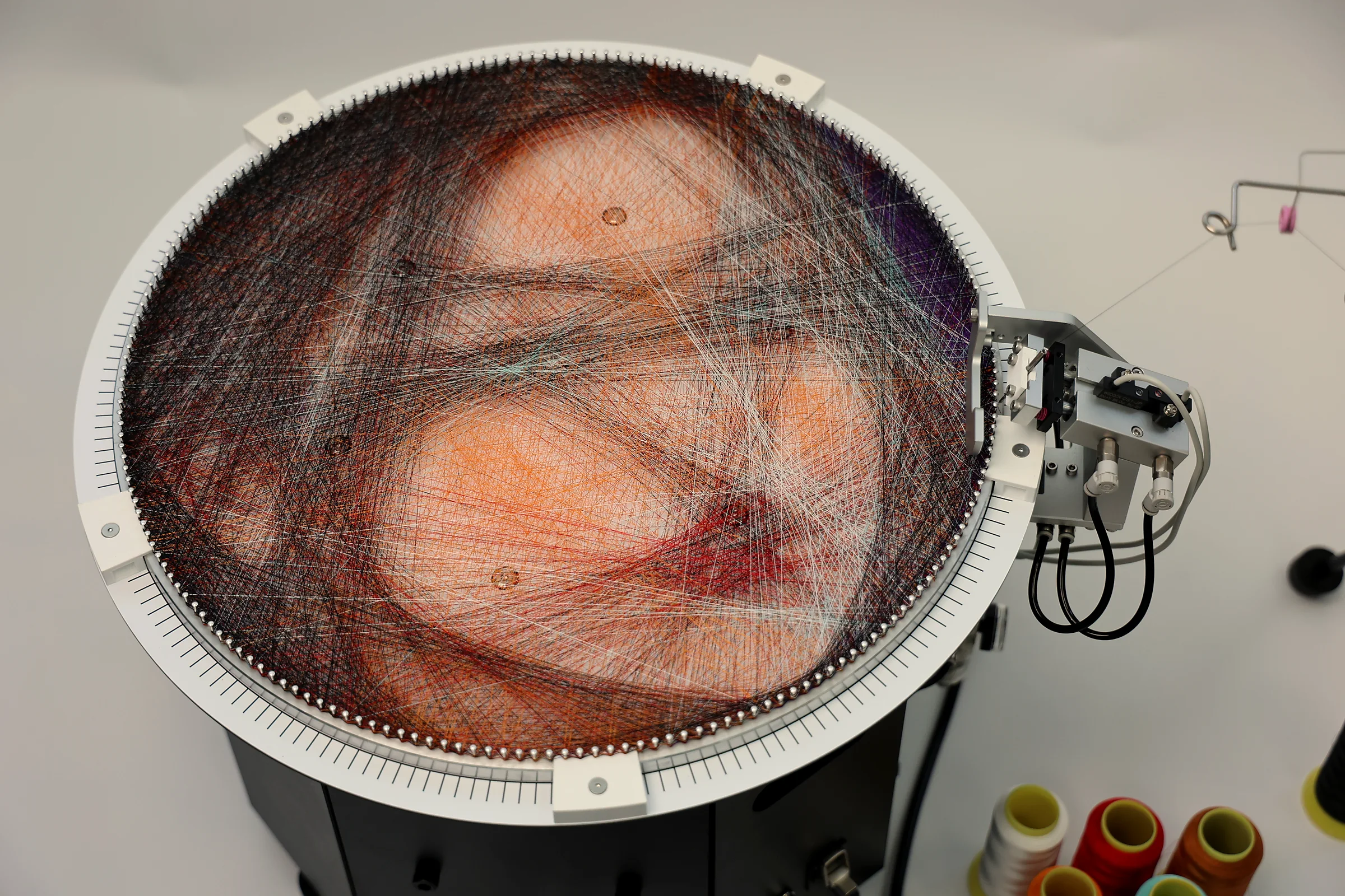 ALINEDECO automatic string art machine with a completed color portrait